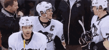 a group of hockey players are standing next to each other and talking to each other .