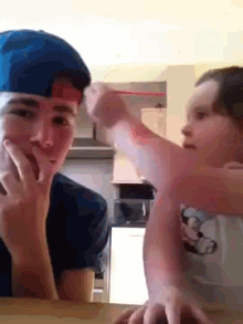 a boy and a girl are sitting at a table talking to each other .