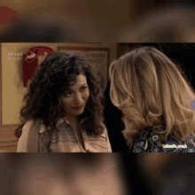 two women are talking in front of a sign that says teatro