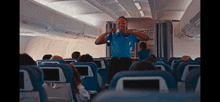 a stewardess stands in front of a row of blue seats on an airplane
