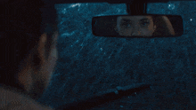 a person is looking at their rear view mirror while driving in the rain