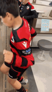 a boy wearing a red and black shirt with the word bar on the sleeve