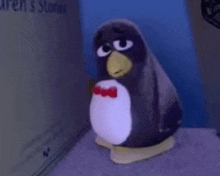 a stuffed penguin wearing a bow tie is sitting on a carpet .