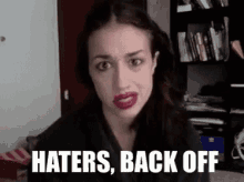 a woman with red lipstick is making a funny face and says `` haters , back off '' .