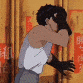 a man in a white tank top is covering his face with his hand