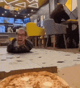 a man is laying on the floor in front of a pizza