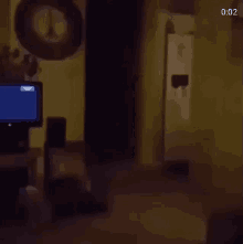 a dark room with a television and a clock on the wall .