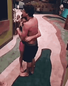 a shirtless man is hugging a woman in a pink bikini .