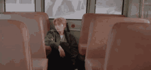 a man sits in the back of a bus looking out a window