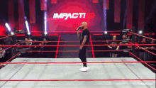 a man stands in a wrestling ring with a microphone in front of a large impact logo