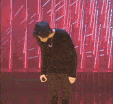 a young man is standing on a stage holding his hands to his chest .