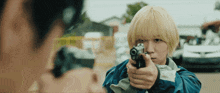 a woman with blonde hair is pointing a gun at another woman