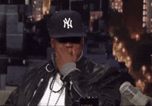 a man wearing a ny hat and a leather jacket
