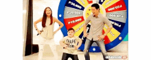a man and two children are dancing in front of a wheel of fortune that says p20,000 on it .