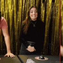 a woman is standing in front of a table with a cake on it and smiling .