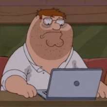 peter griffin is sitting at a table with a laptop