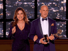 a woman in a purple dress stands next to a man in a purple suit