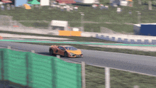 a yellow sports car is driving down a race track