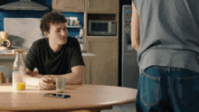 a man sits at a table with a glass of orange juice on it