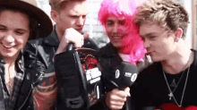 a man in a pink wig is holding a microphone in front of a group of young people