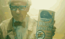 a man in a bow tie holds a can of whale laxative