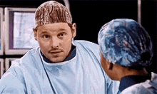 a man in a surgical gown is talking to a woman in a scrub cap .