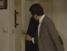 a man in a suit and tie is standing in a room with boxes and a large clock
