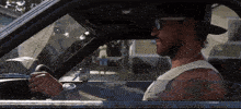 a man wearing sunglasses and a hat driving a car