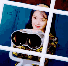 a woman with blue hair is holding a pair of binoculars in front of a window