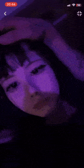 a girl is taking a selfie in the dark with a purple light behind her .
