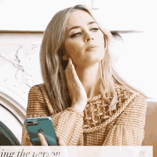 a woman in a plaid shirt holds a cell phone in her hand