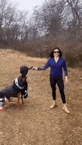 a woman is standing in a field holding a gun to a mannequin .