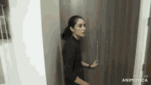 a woman in a black shirt is standing in front of a wooden cabinet made by animatica