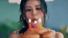 a close up of a woman blowing out candles on a birthday cake .