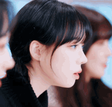 a close up of a woman 's face with a ponytail and bangs
