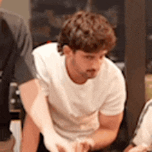 a man in a white t-shirt is sitting in a chair .