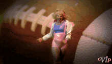 a woman in a pink outfit is screaming in front of a football with gvip in the corner