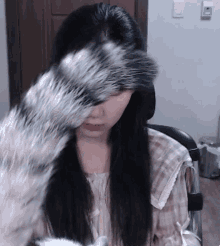 a woman is covering her face with a furry object