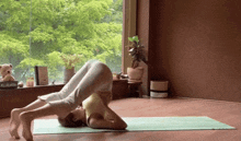 a woman is doing a yoga pose in front of a window with a mccallister book on the window sill