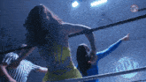 two women wrestling in a ring with a npc logo on the wall behind them