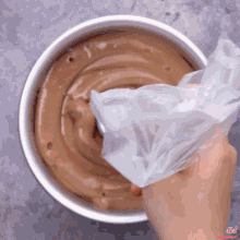 a person is holding a plastic bag over a bowl of chocolate batter
