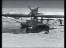 a black and white photo of a seaplane in the ice