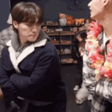 a group of young men are standing next to each other in a room . one of the men is wearing a lei .