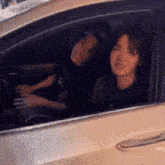 a man and a woman are sitting in a car looking out the window .