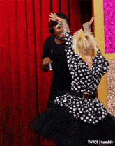 a woman in a polka dot dress is dancing with a man wearing headphones