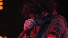 a man is singing into a microphone in front of a green background