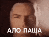 a close up of a man 's face with the words " alo pasha " written in white