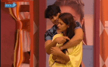 a man and woman hugging in front of a sign that says 24hrs live channel