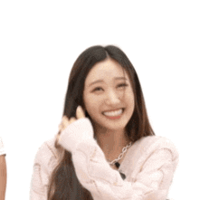 a woman wearing a pink sweater is smiling and covering her face with her hand