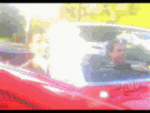 a man is driving a red car with a watermark that says zdark